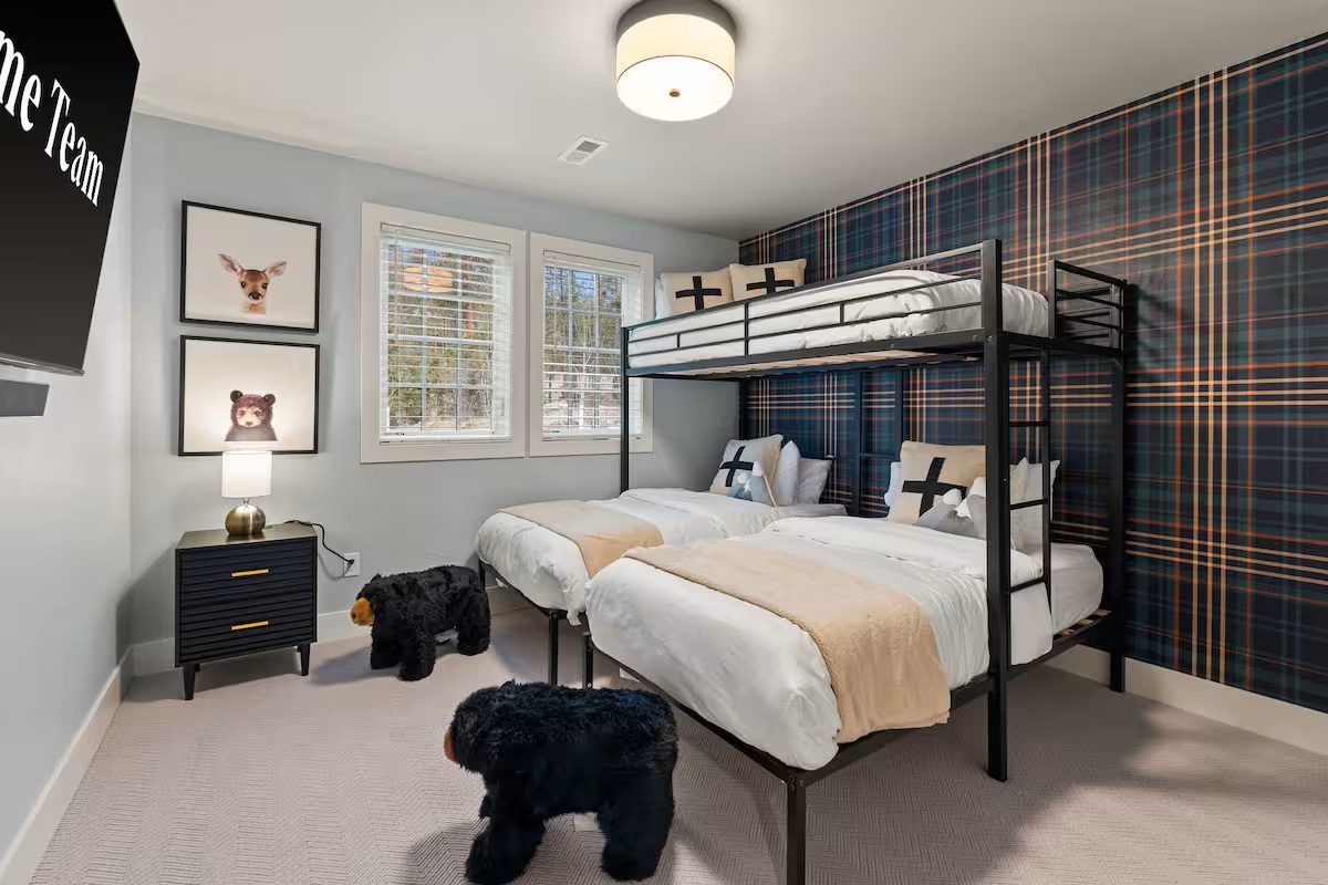 Family-friendly bunk room with plaid wallpaper and children’s books